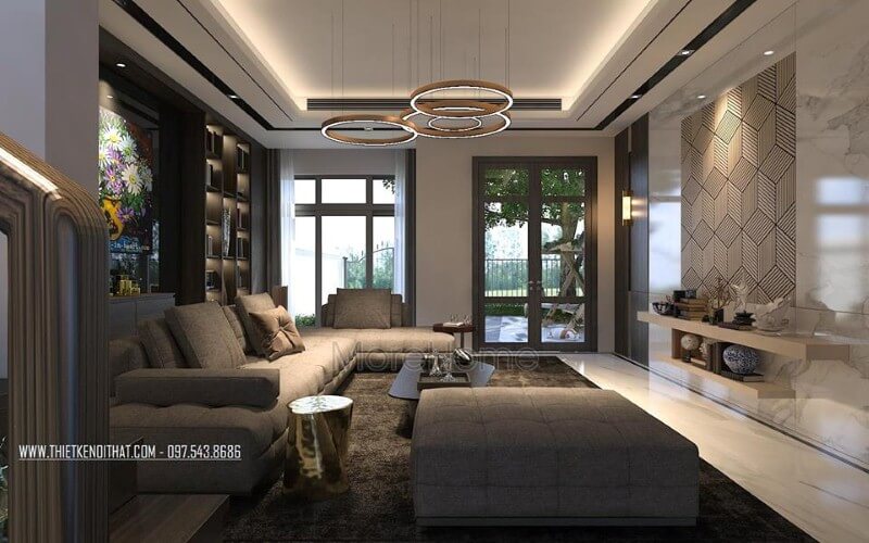 Phòng khách biệt thự đầy ấm cúng với tâm điểm là bộ sofa hiện đại kiểu dáng góc tối ưu diện tích được bọc vải êm ái màu xám tinh tế. Thiết kế phòng khách biệt thự